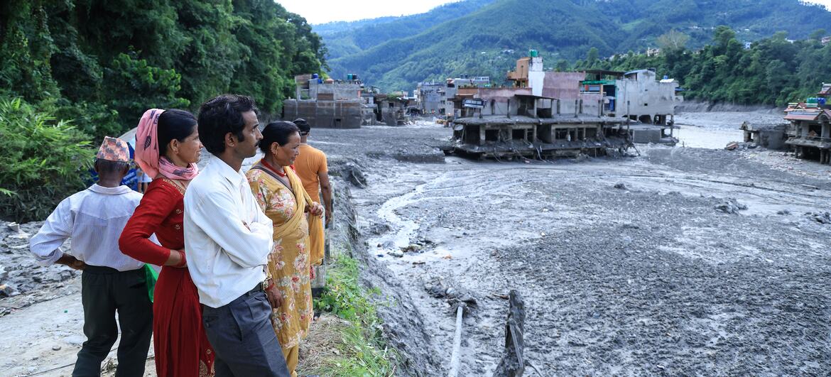 Local residents look out over the flood-devastated riverbank in Nepal